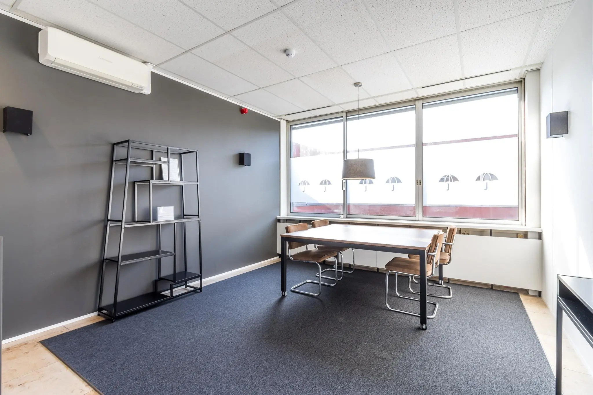 Modern ingerichte vergaderruimte aan de Jan van Eycklaan met een tafel, stoelen, open kast en groot raam met veel daglicht.